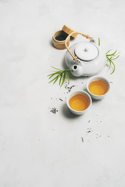 アジアのお茶のコンセプト、お茶、ティーポット、ティーセット、箸、竹マットの2つの白いカップ Premium写真