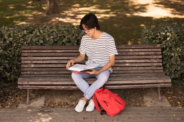Foto gratuita uomo teenager asiatico con il libro di testo sul banco
