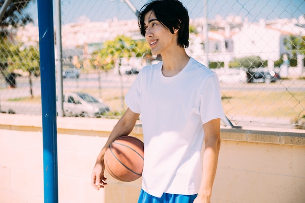 Азиатский подросток студент стоял с баскетболом