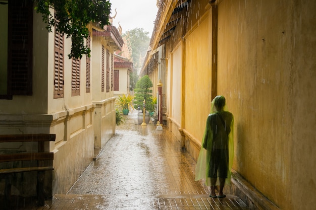 Asian teen waiting for the monsoon rain to stop.