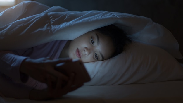 Premium Photo | Asian teenage girls lie smart phone on line in the night on  the bed at home