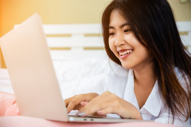 Asian teenage woman use laptop on bed