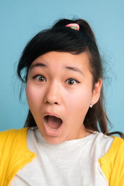 Asian teenager's close up portrait isolated on blue studio