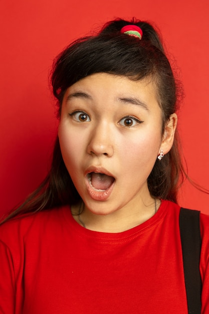Asian teenager's close up portrait isolated on red studio background