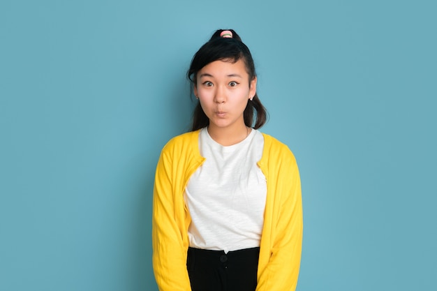 Asian teenager's portrait isolated on blue studio background