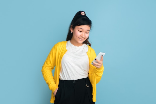 Asian teenager's portrait isolated on blue studio background