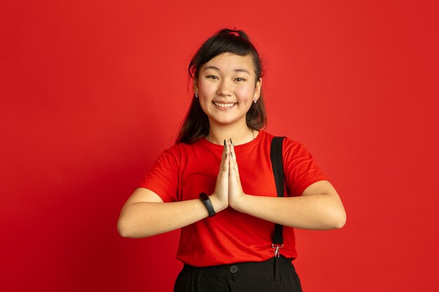 Asian teenager's portrait isolated on red  space. Beautiful female brunette model with long hair in casual style