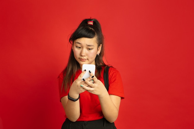 Asian teenager's portrait isolated on red  space