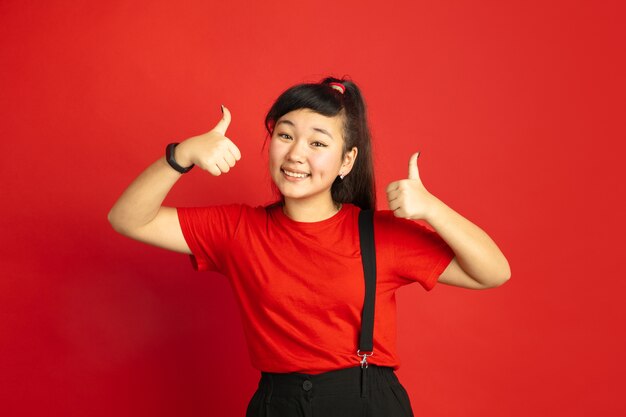 Asian teenager's portrait isolated on red  space