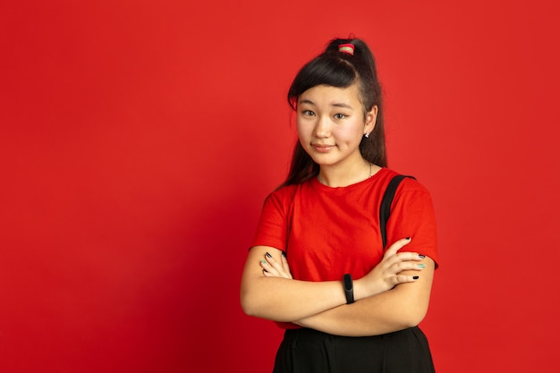 Asian teenager's portrait isolated on red studio background