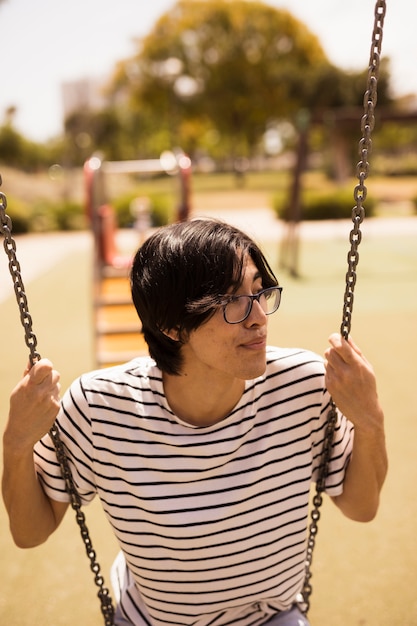 Asian teenager sitting on swings