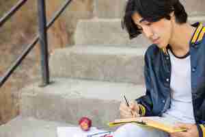 Free photo asian teenager sitting with book on stairs