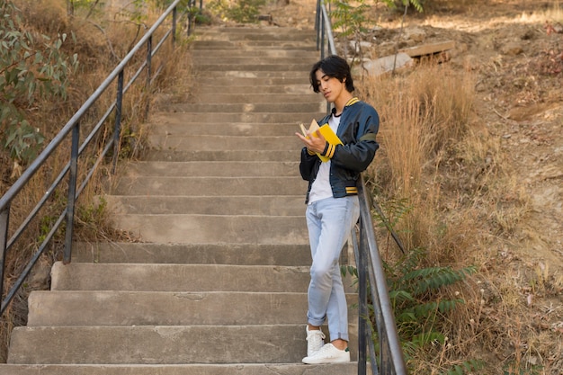 Asian teenager standing with book on stairs