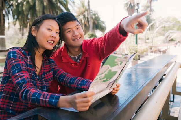 Asian traveler couple holding a map and looking for directions.