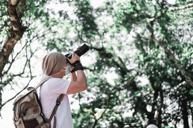 コピースペースで公園で写真を撮るバックパックを持つアジアの旅行者の男旅行写真家職業と休日のコンセプト