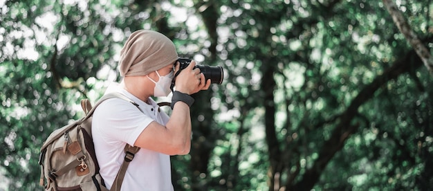 Asian traveler man with backpack taking a photo in the park with copy space Travel photographer Vocation and holiday concept