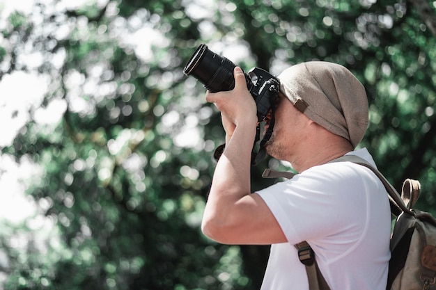 Asian traveler man with backpack taking a photo in the park with copy space Travel photographer Vocation and holiday concept