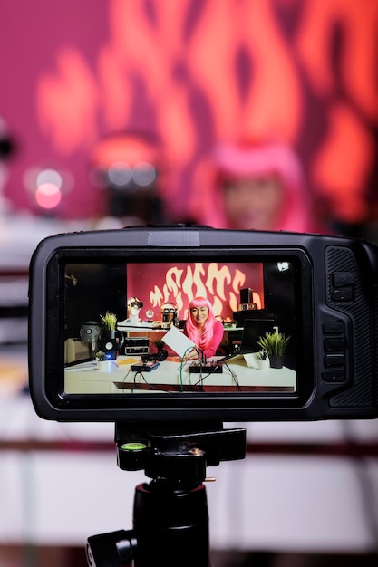 アジアのビデオブロガーは、ビデオブログスタジオでポッドキャストを録画しながら、製品をレビューするカメラでホワイトボックスを宣伝します。プロの放送機器を使用して vlog を撮影するコンテンツクリエイターの女性