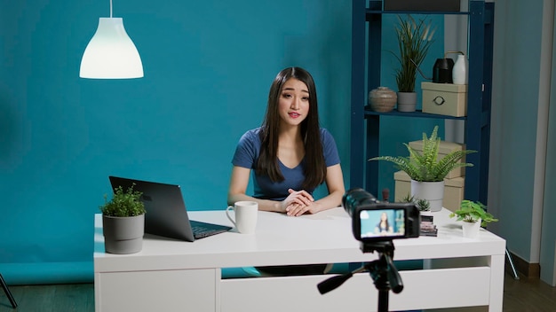 Asian vlogger filming beauty tutorial with smartphone camera, recording makeup video with cosmetics. Beauty influencer streaming online internet broadcast with glam product, videoblog.