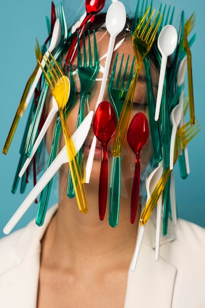 Foto gratuita donna asiatica che è ricoperta di stoviglie in plastica colorata