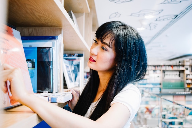 Asian woman browsing bookshelves 