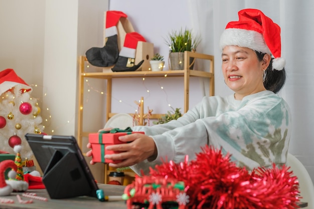 아시아 여성은 집에서 태블릿 화상 통화 친구와 함께 새해와 크리스마스 파티를 축하합니다