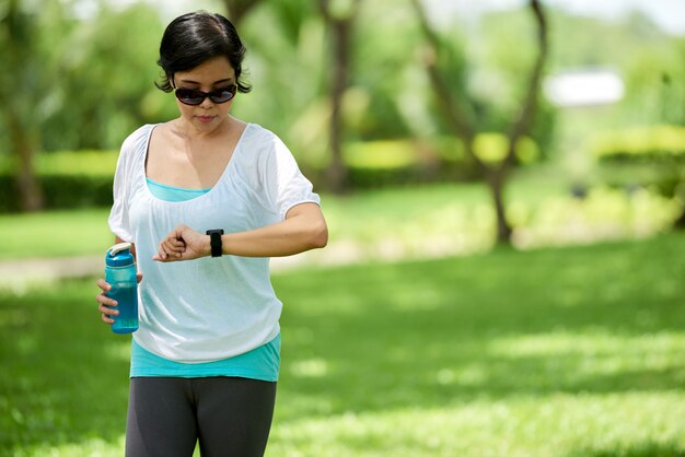 Азиатская женщина проверяет фитнес браслет