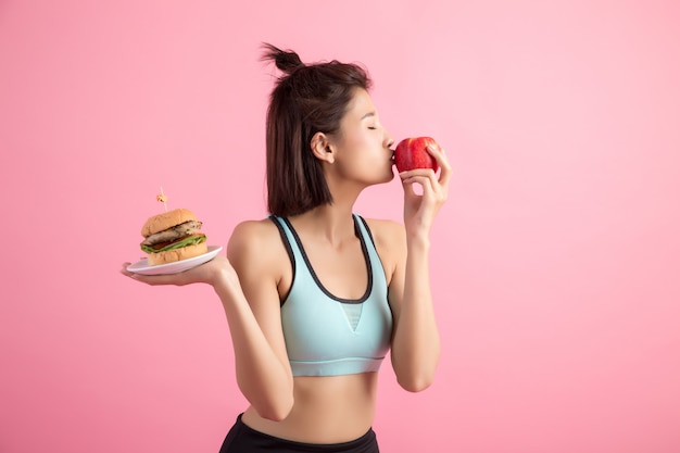 햄버거와 핑크에 빨간 사과 사이 선택하는 아시아 여자