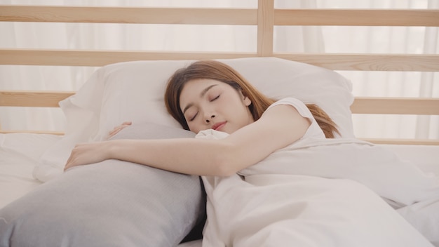 Free photo asian woman dreaming while sleeping on bed in bedroom