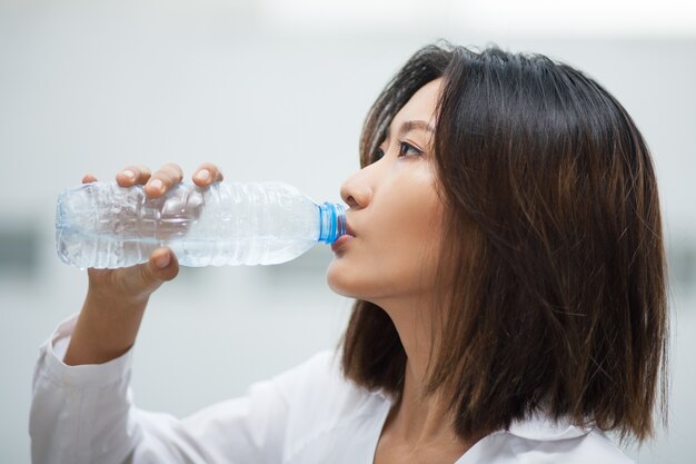 Азиатская женщина питьевой воды из пластиковой бутылки
