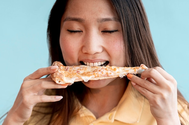 Asian woman eating a slice of pizza close-up