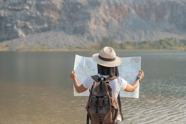 Asian woman enjoying beauty of nature looking at mountain lake