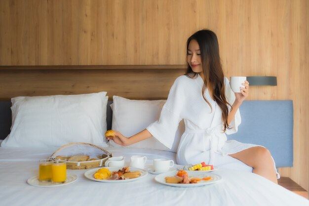 アジアの女性がベッドで朝食を楽しんで