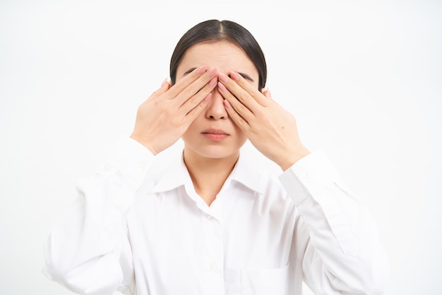 Free photo asian woman entrepreneur businesswoman shuts her eyes with hands stands blindfolded against white st