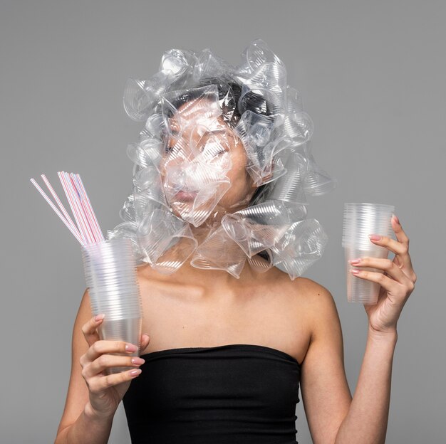 Asian woman face being covered in plastic cups while holding other plastic objects