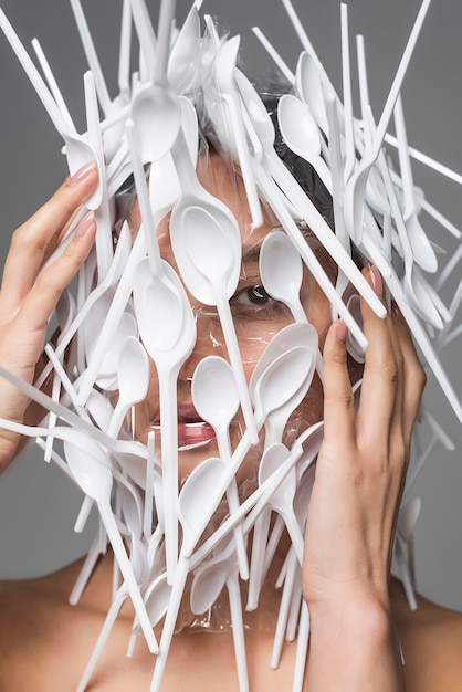 Fronte della donna asiatica che è coperto nel primo piano di plastica bianco