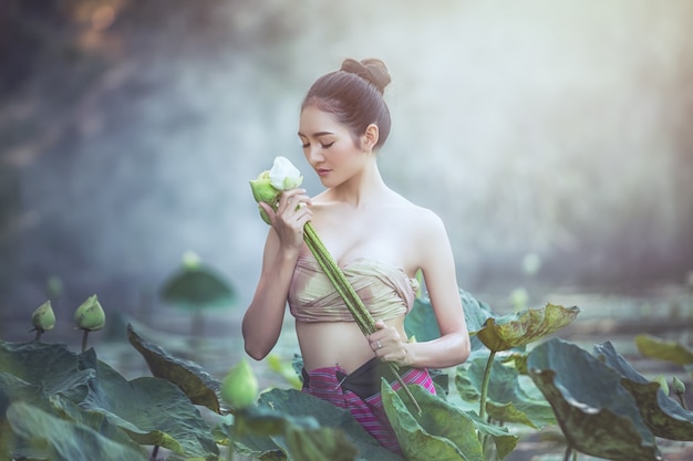 アジアの女性は 庭 タイで蓮の花を収穫します プレミアム写真