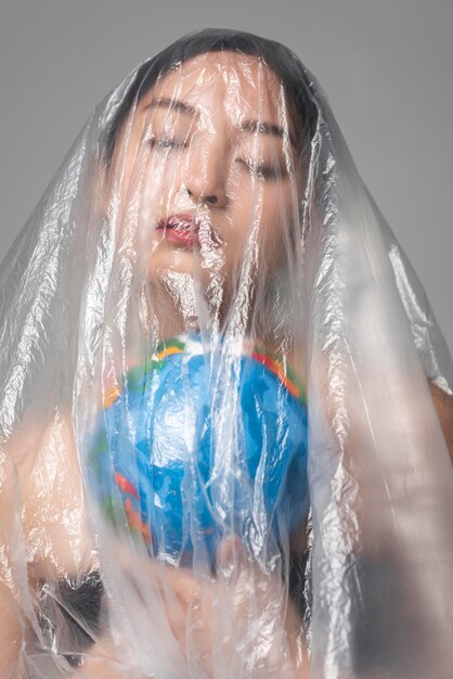 플라스틱으로 덮여있는 동안 지구 지구본을 들고 아시아 여자