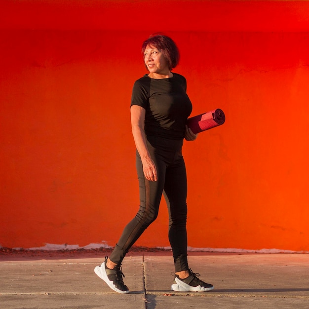 Free photo asian woman holding a fitness mat