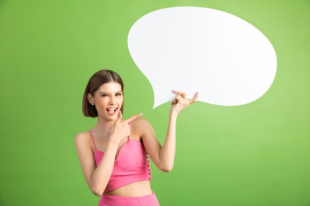 Asian woman holding and looking up to speech bubble with empty space for text on green 