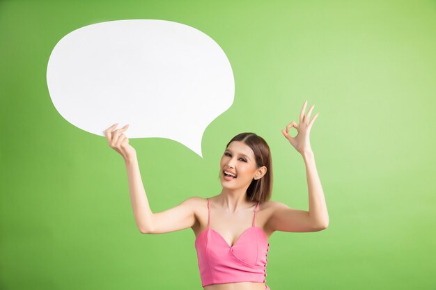 Asian woman holding and looking up to speech bubble with empty space for text on green 