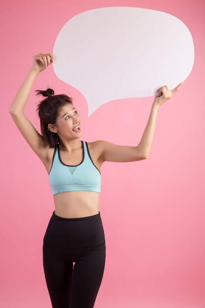 Asian woman holding and looking up to speech bubble with empty space for text on pink