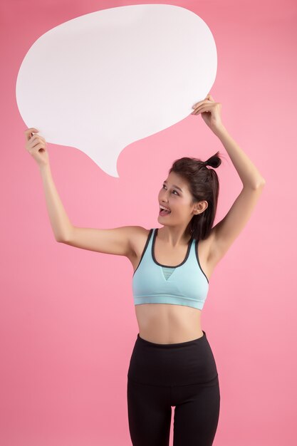 Asian woman holding and looking up to speech bubble with empty space for text on pink