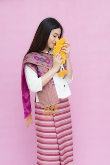ピンク​の​背景​に​隔離された​マリー​ゴールド​の​花輪​を​持つ​アジア​の​女性