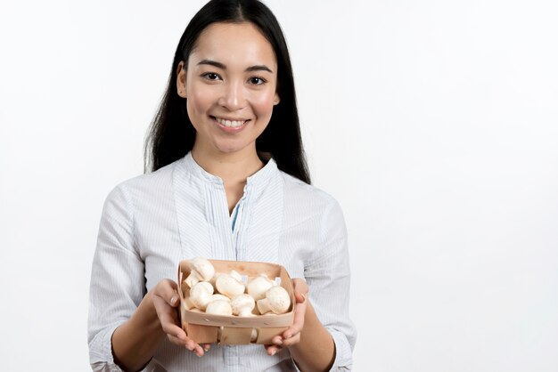 アジアの女性の白い背景に対してキノコ容器を保持