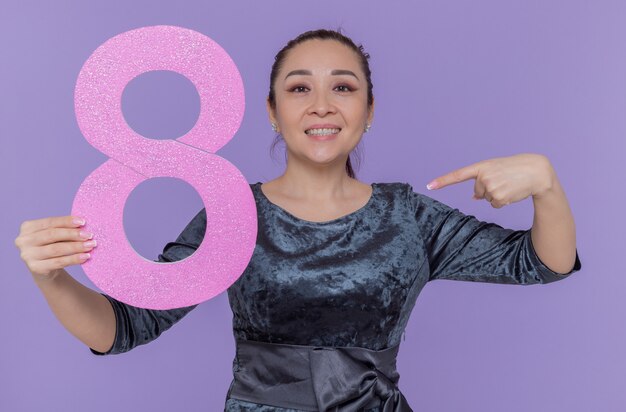 Asian woman holding number eight made from cardboard pointing