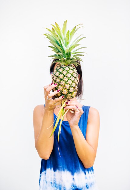 Asian woman holding pineapple covering face