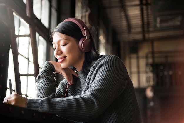 아시아 여자 듣기 음악 헤드폰 쓰기 노트북 개념