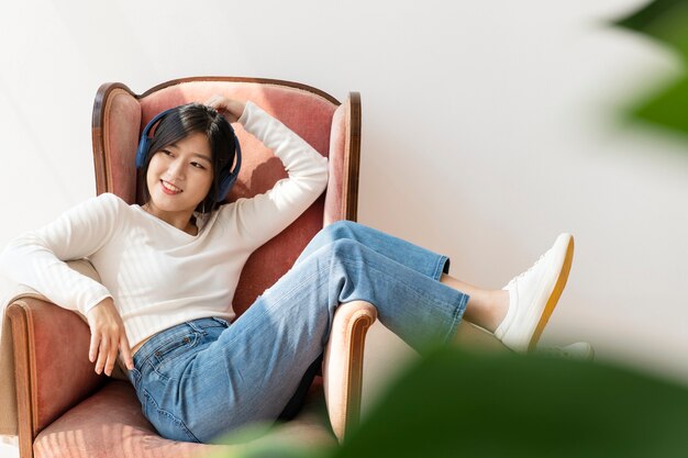 Free Photo asian woman listening to music on a red sofa