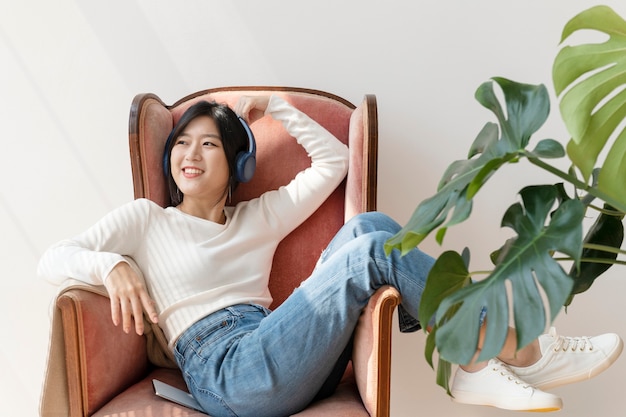 Free photo asian woman listening to music on a red sofa